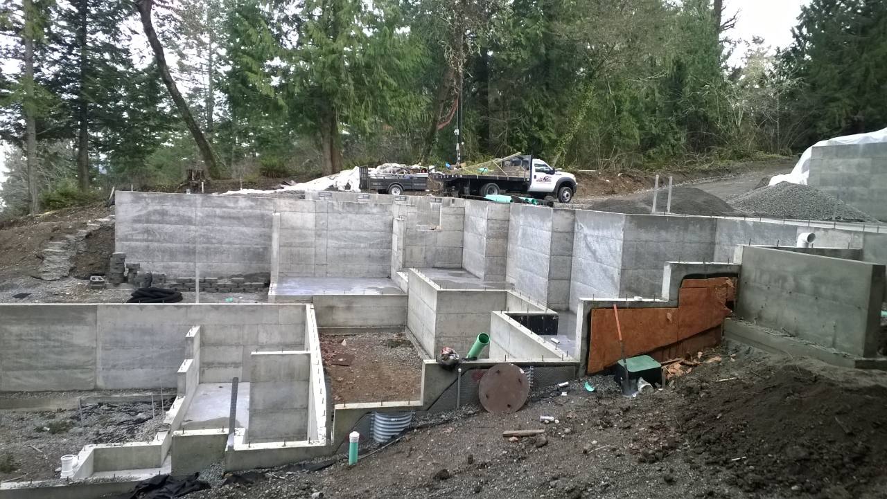 Multi-level concrete foundation under construction on a wooded site
