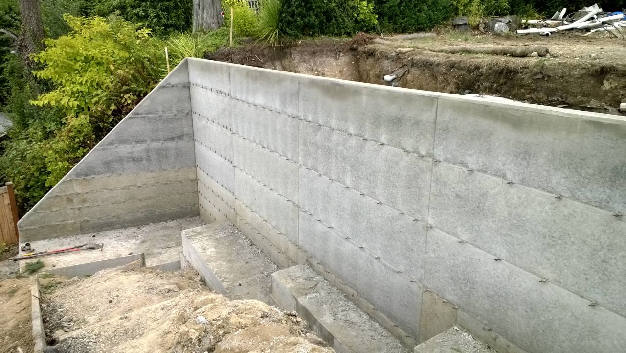 Close view of tall poured concrete retaining walls and stepped footings